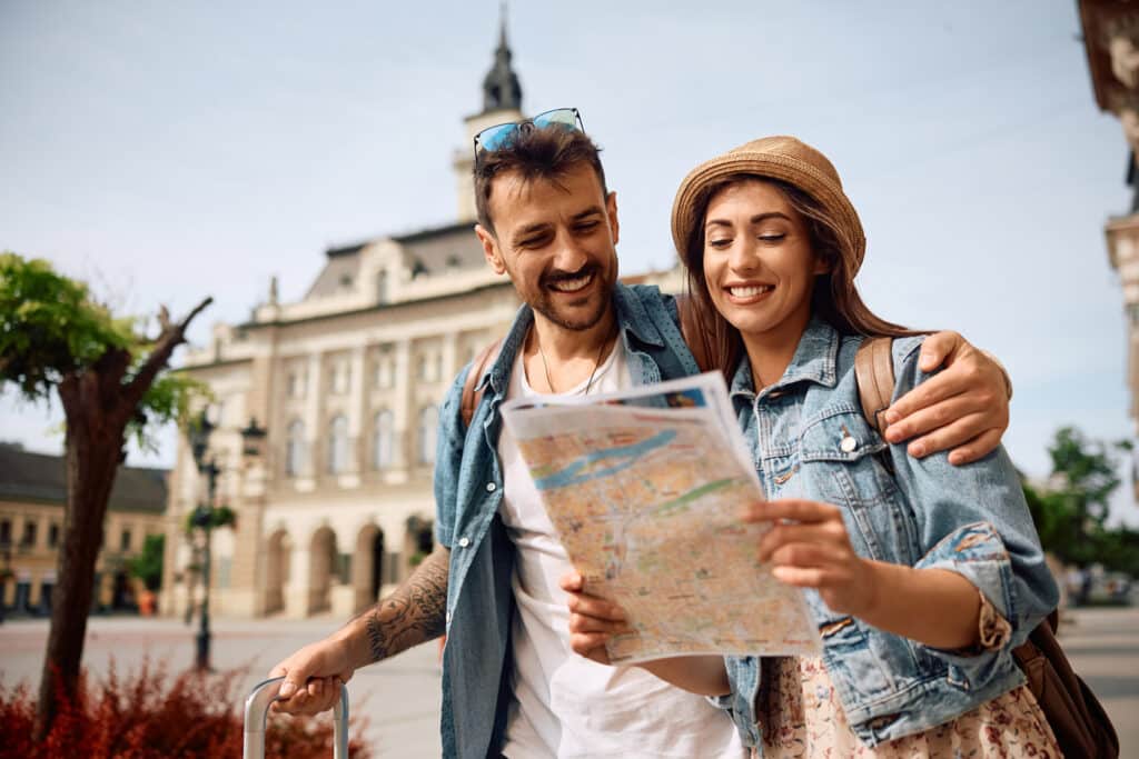 Happy couple enjoying in travel while exploring a map during their walk through the town.