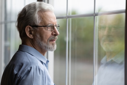 Senior man looking out a window in thought