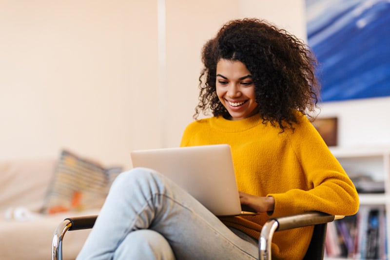 Woman sitting in a chair smiling with her laptop computer